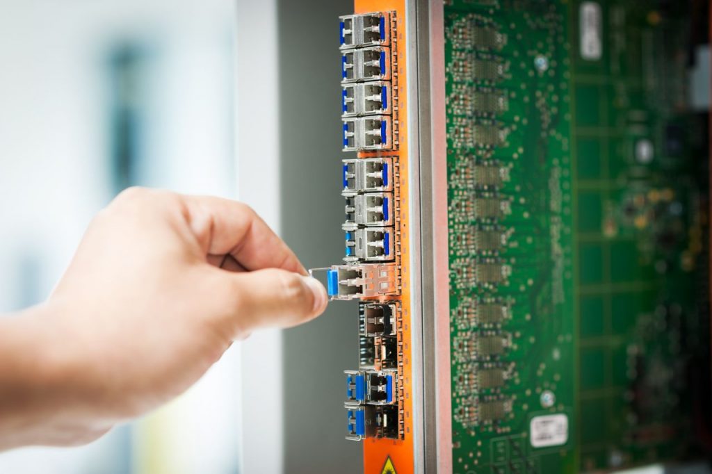 Home An individual connecting a cable into a network server port indoors, focusing on technology setup.