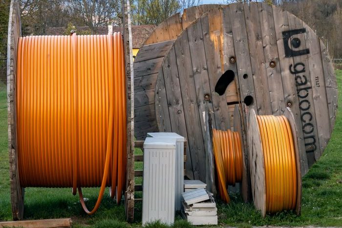 Home Wooden spools holding orange cables in a rural outdoor area.